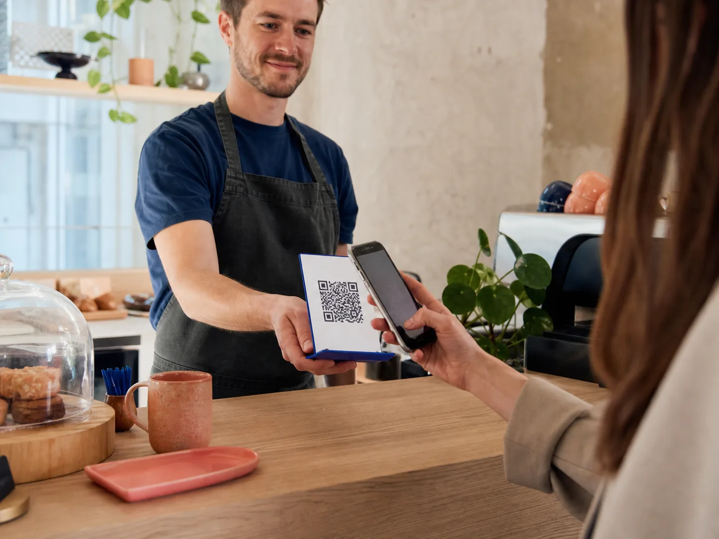 A customer scanning a payment QR at a café counter